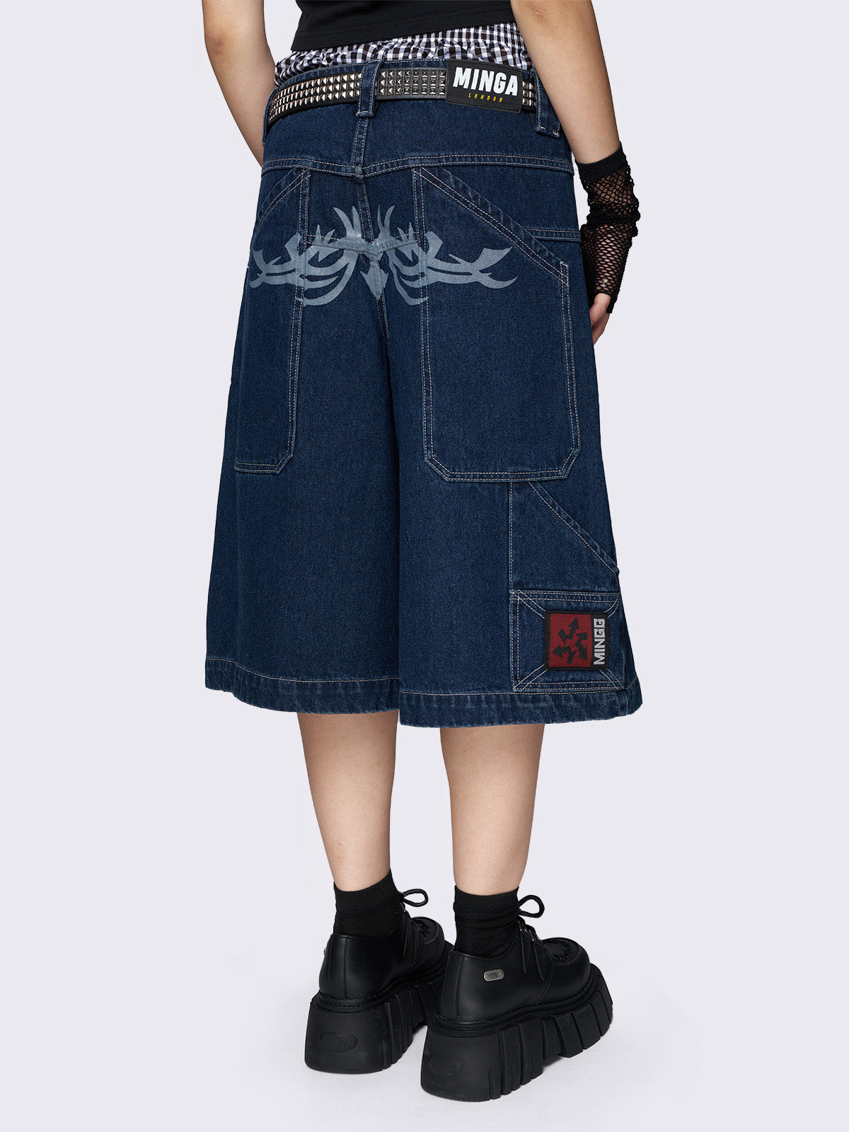 Blue longline denim shorts with carpenter pockets, a tattoo back print, and a relaxed fit. Featuring a regular waist and zip fly with button fastening.