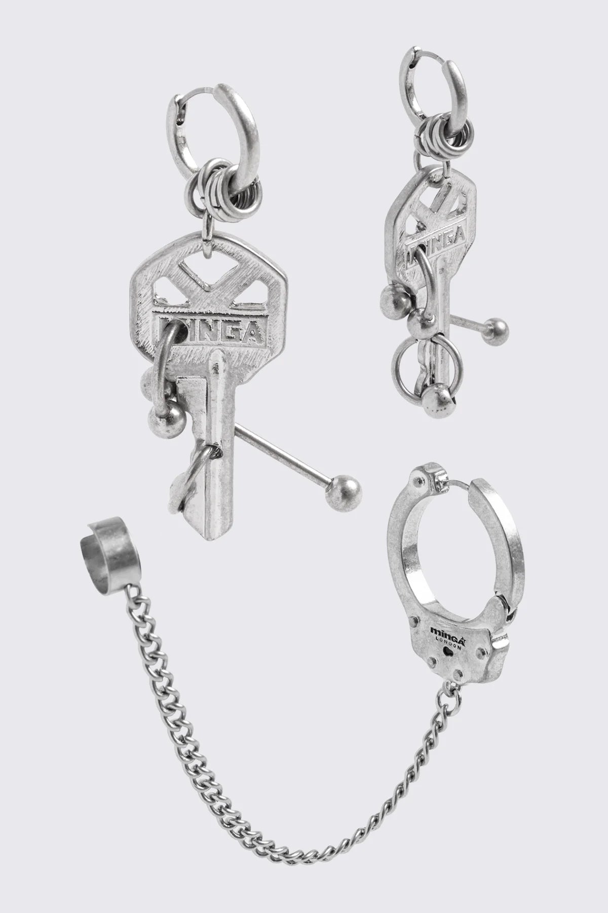 Silver metal hoop earring with key charm, chain ear cuff and piercing details in a grunge goth style.