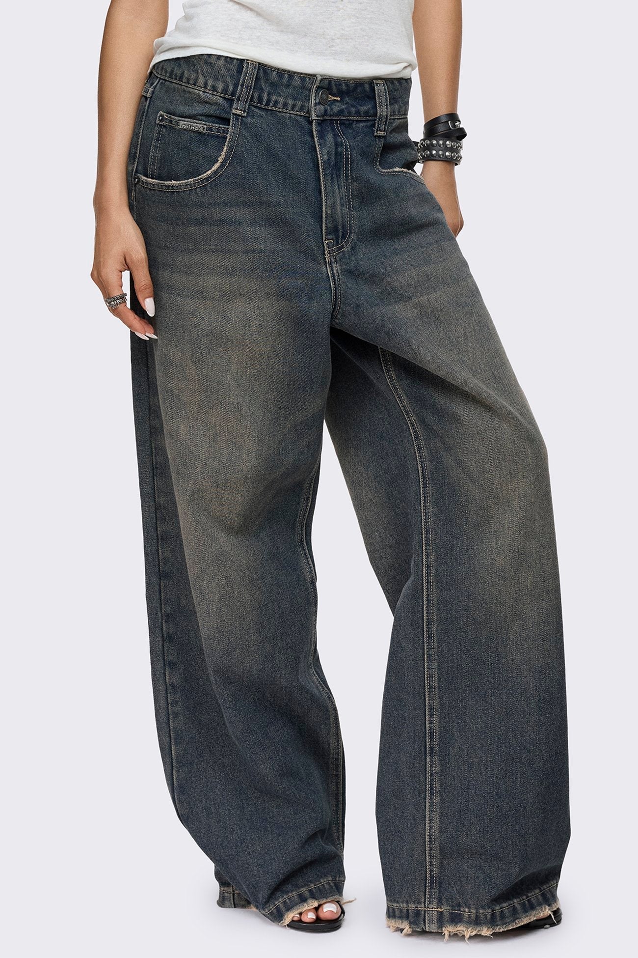 Washed dirty blue jeans with a faded finish, low-rise waist, straight baggy leg and five-pocket design.