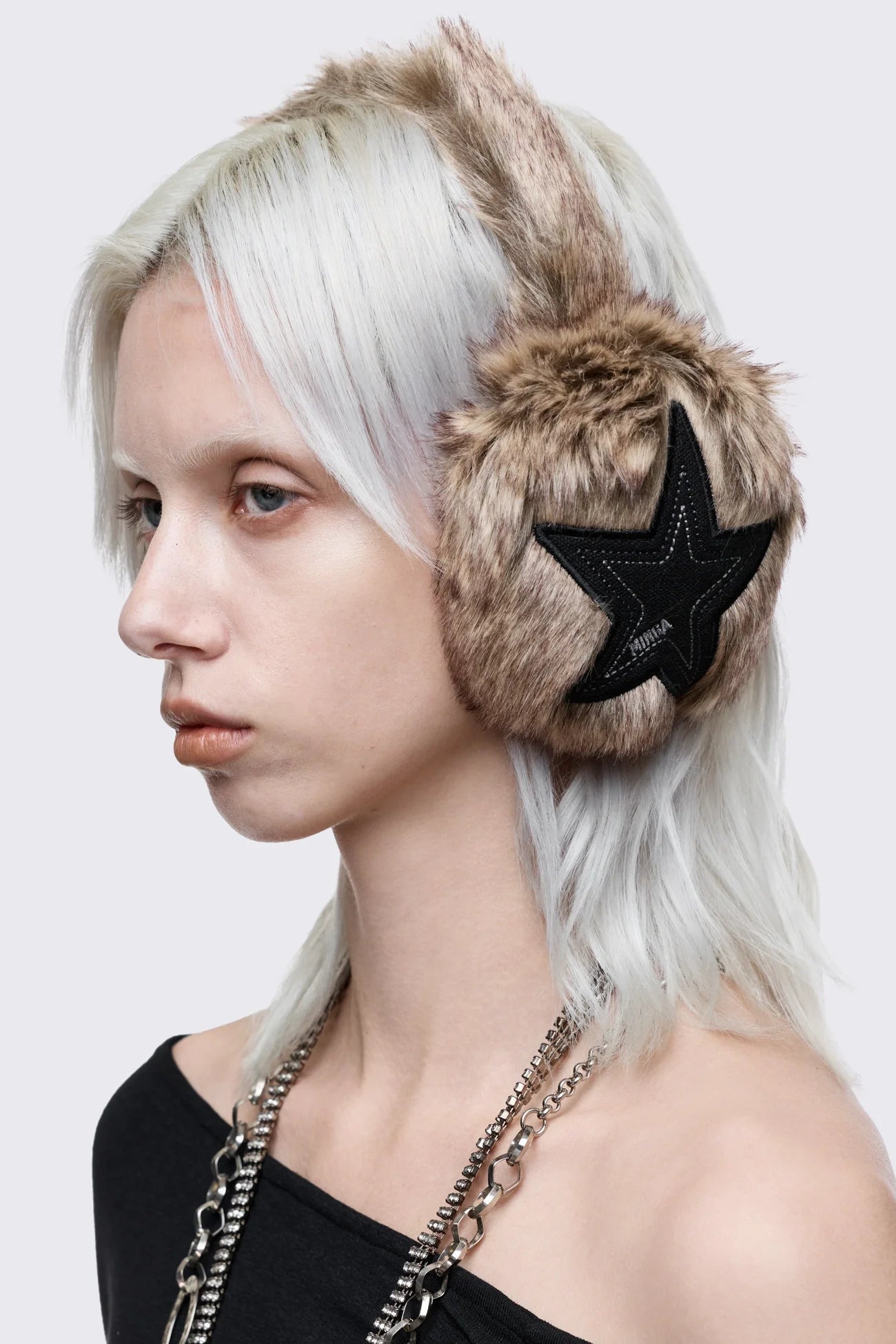 Faux fur earmuffs in beige and brown featuring stars embroidered patch in black.