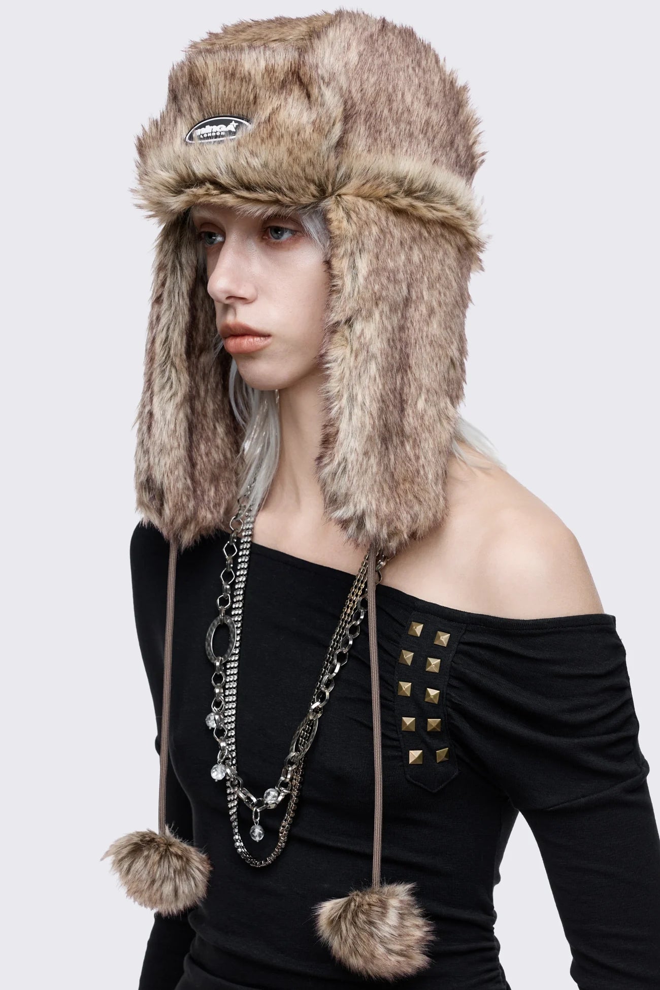Beige faux fur trapper hat with minga rubber logo detail and ear flaps
