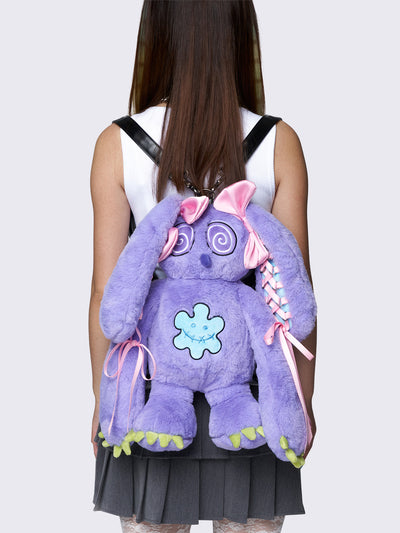 Purple furry bunny plush backpack with pink lace-up ribbons and bows on the bunny ears, embroidered details, and a back zipper pocket.