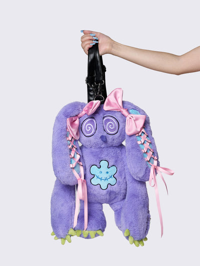 Purple furry bunny plush backpack with pink lace-up ribbons and bows on the bunny ears, embroidered details, and a back zipper pocket.