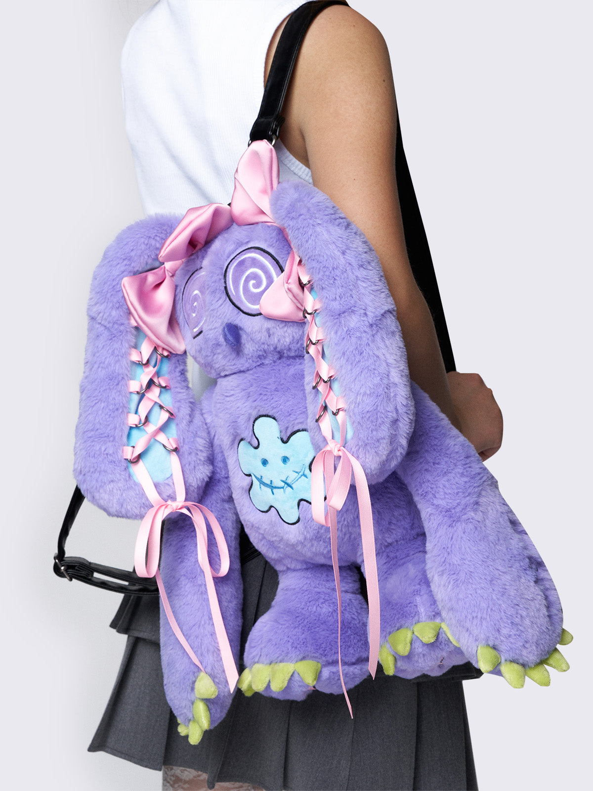 Purple furry bunny plush backpack with pink lace-up ribbons and bows on the bunny ears, embroidered details, and a back zipper pocket.