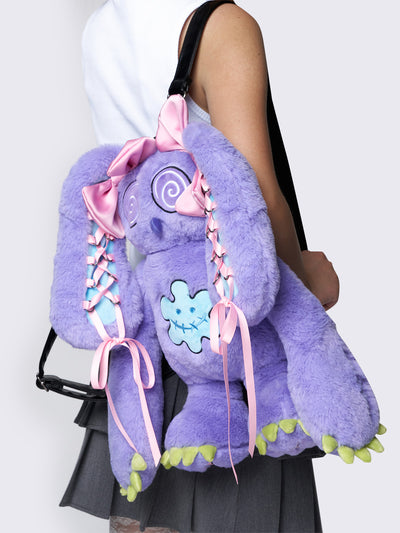 Purple furry bunny plush backpack with pink lace-up ribbons and bows on the bunny ears, embroidered details, and a back zipper pocket.