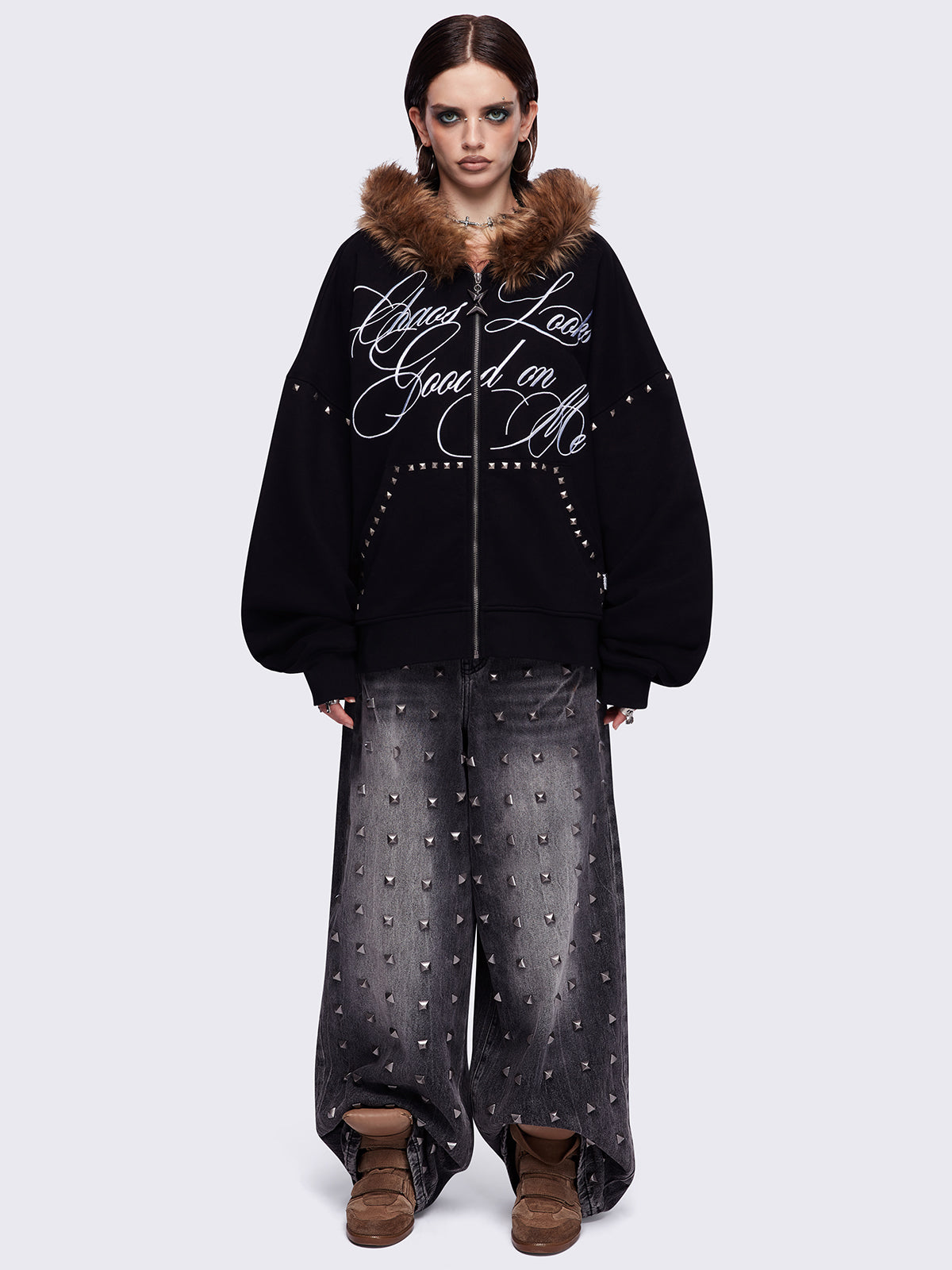 Black zip up hoodie jacket featuring a brown faux fur hood, "Chaos looks good on me" graphic embroidery and stud details.