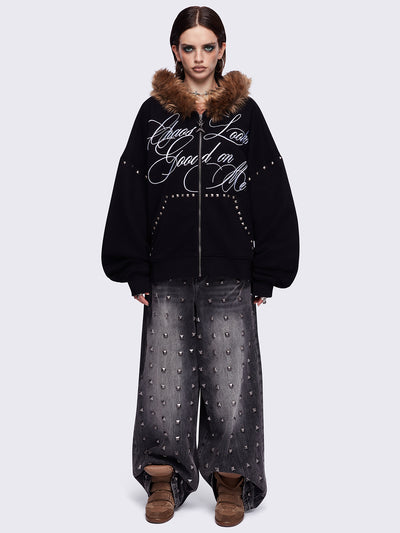 Black zip up hoodie jacket featuring a brown faux fur hood, "Chaos looks good on me" graphic embroidery and stud details.