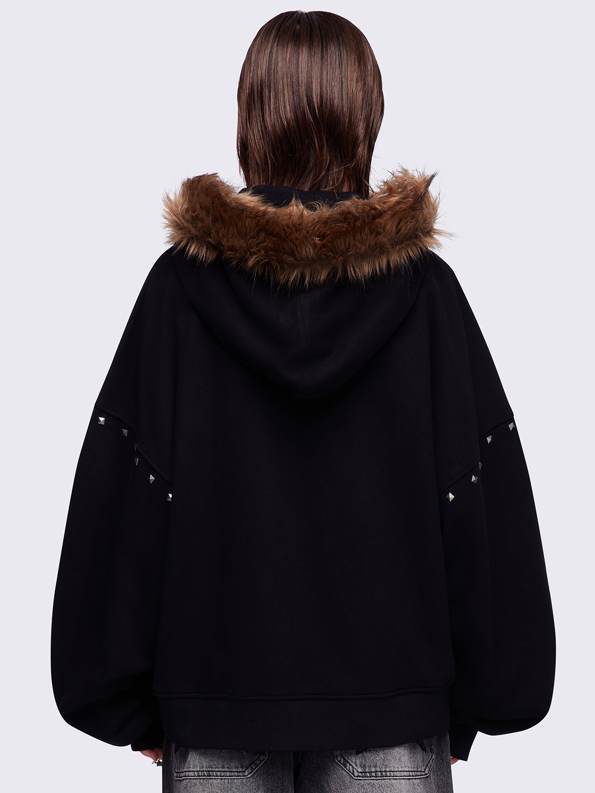 Black zip up hoodie jacket featuring a brown faux fur hood, "Chaos looks good on me" graphic embroidery and stud details.