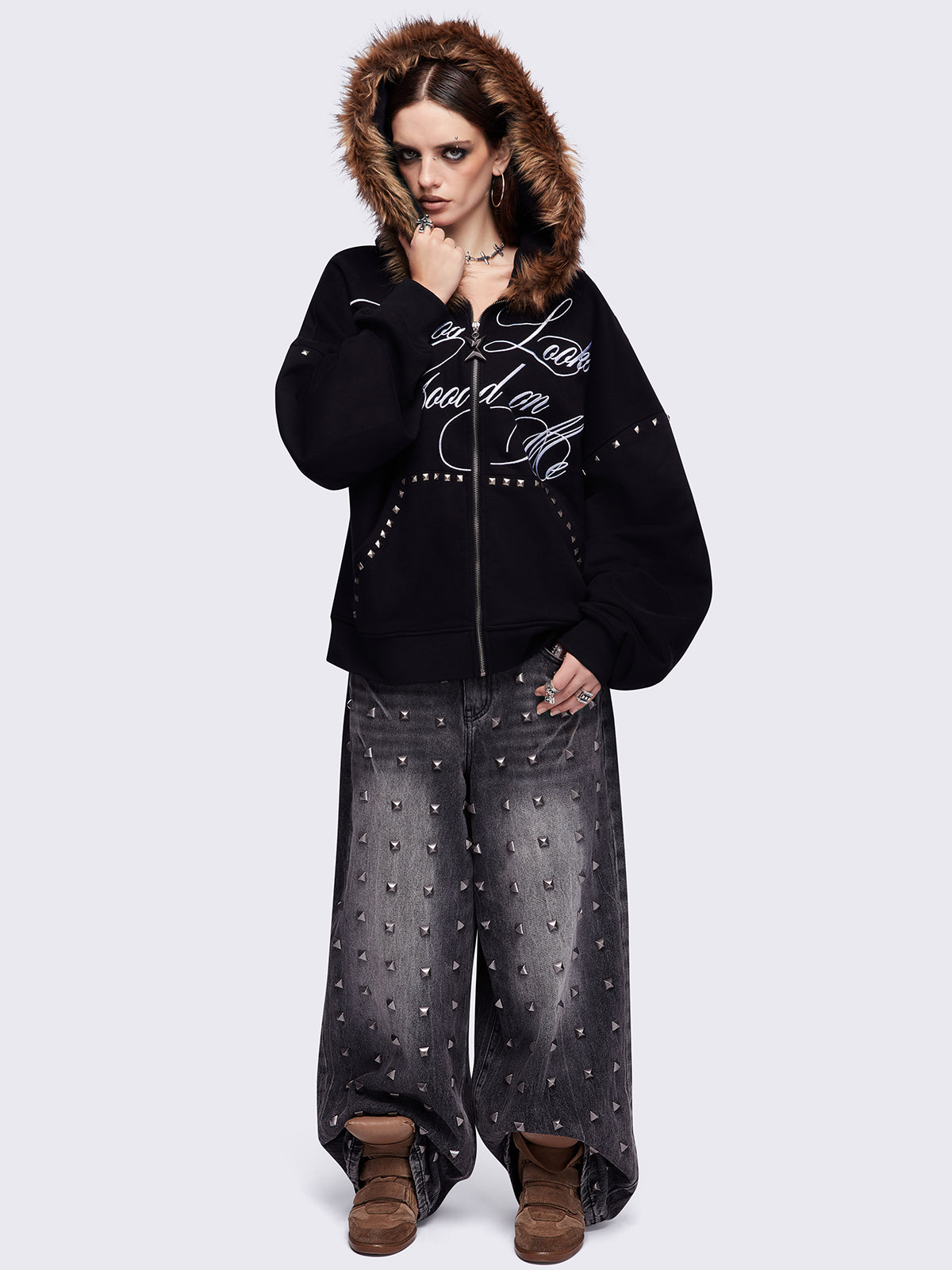 Black zip up hoodie jacket featuring a brown faux fur hood, "Chaos looks good on me" graphic embroidery and stud details.
