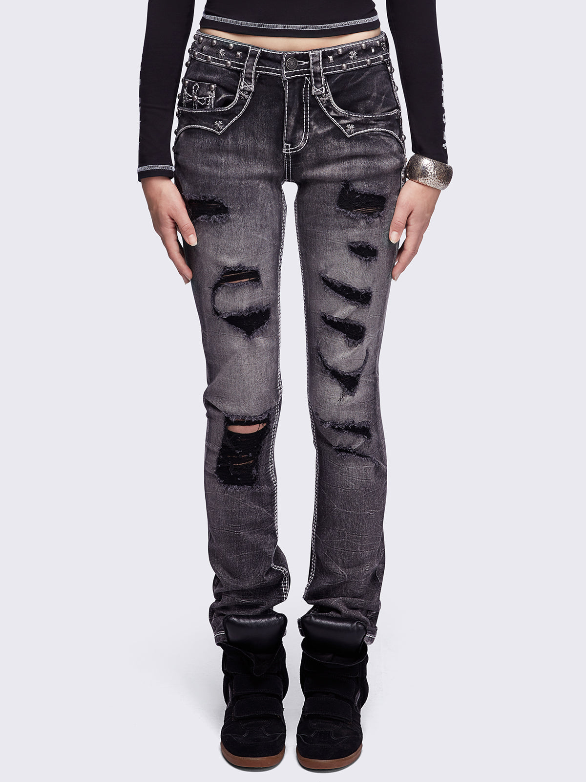 Black washed skinny jeans featuring ripped and stud details, white contrast stitching, embroidered back pocket and raw frayed hems.