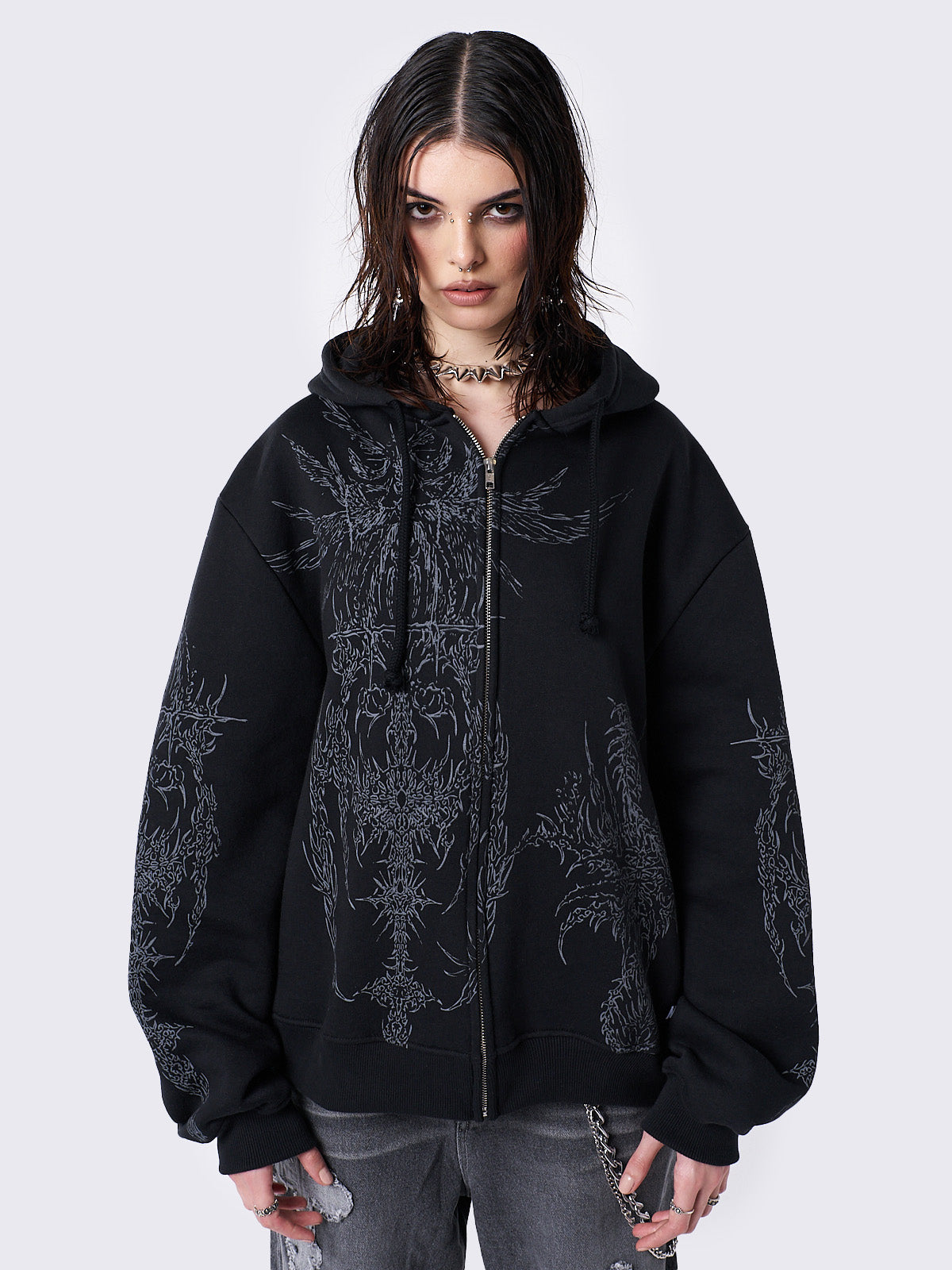 Oversized black zip-up hoodie with grunge graphic prints, drawstring hood, and ribbed trims. Y2K and acubi-inspired streetwear.