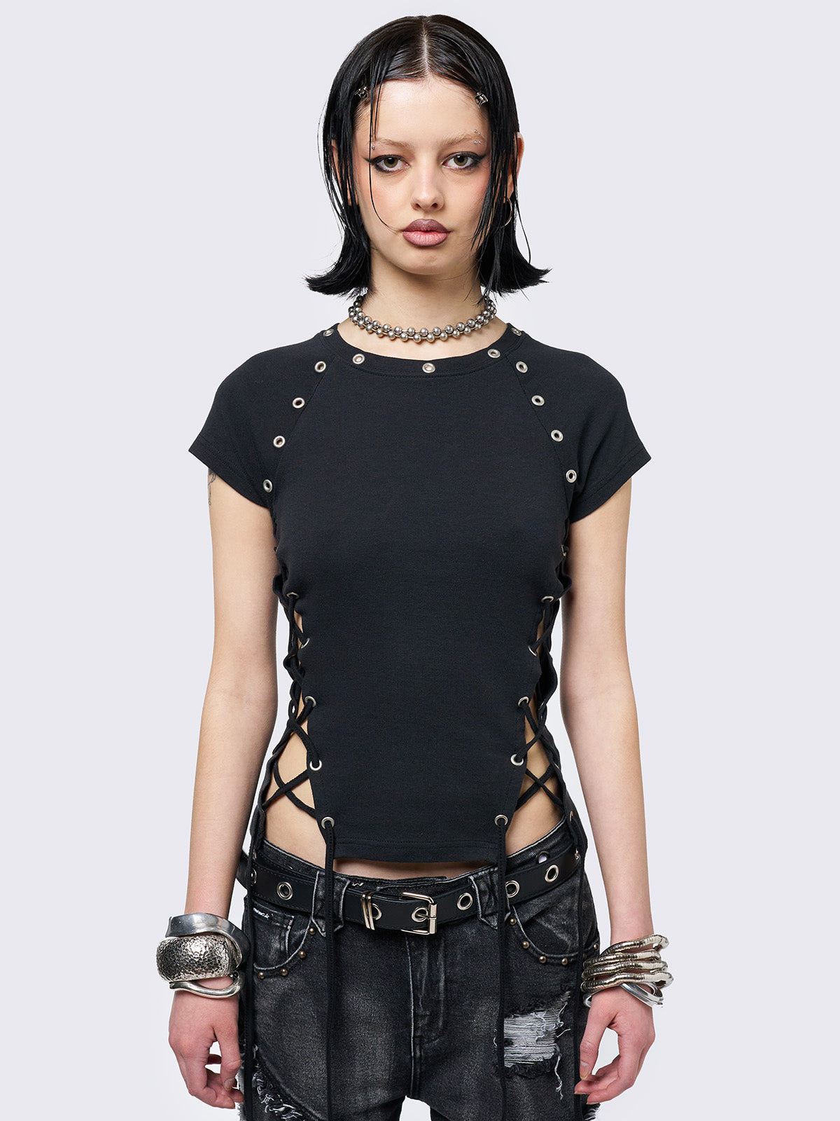 Black baby tee with adjustable lace-up sides and eyelet details. Grunge-inspired style. 