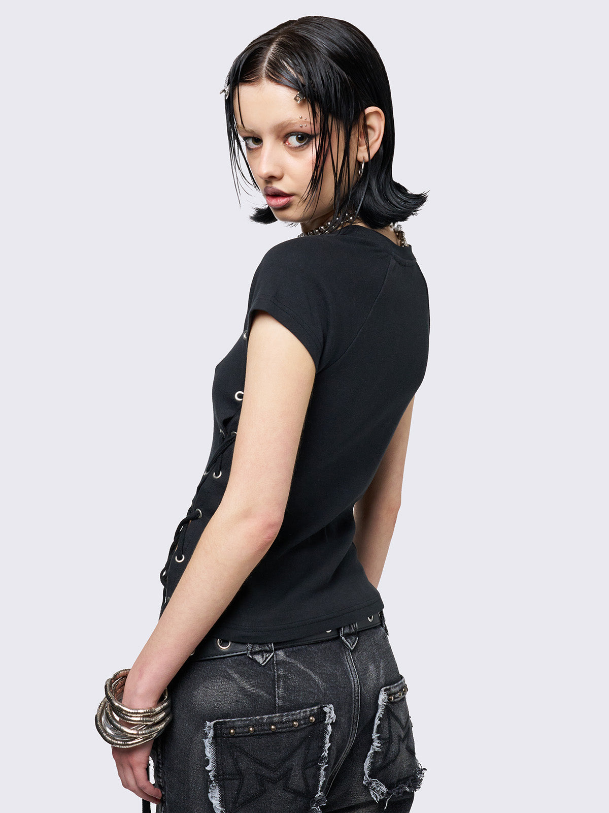 Black baby tee with adjustable lace-up sides and eyelet details. Grunge-inspired style. 