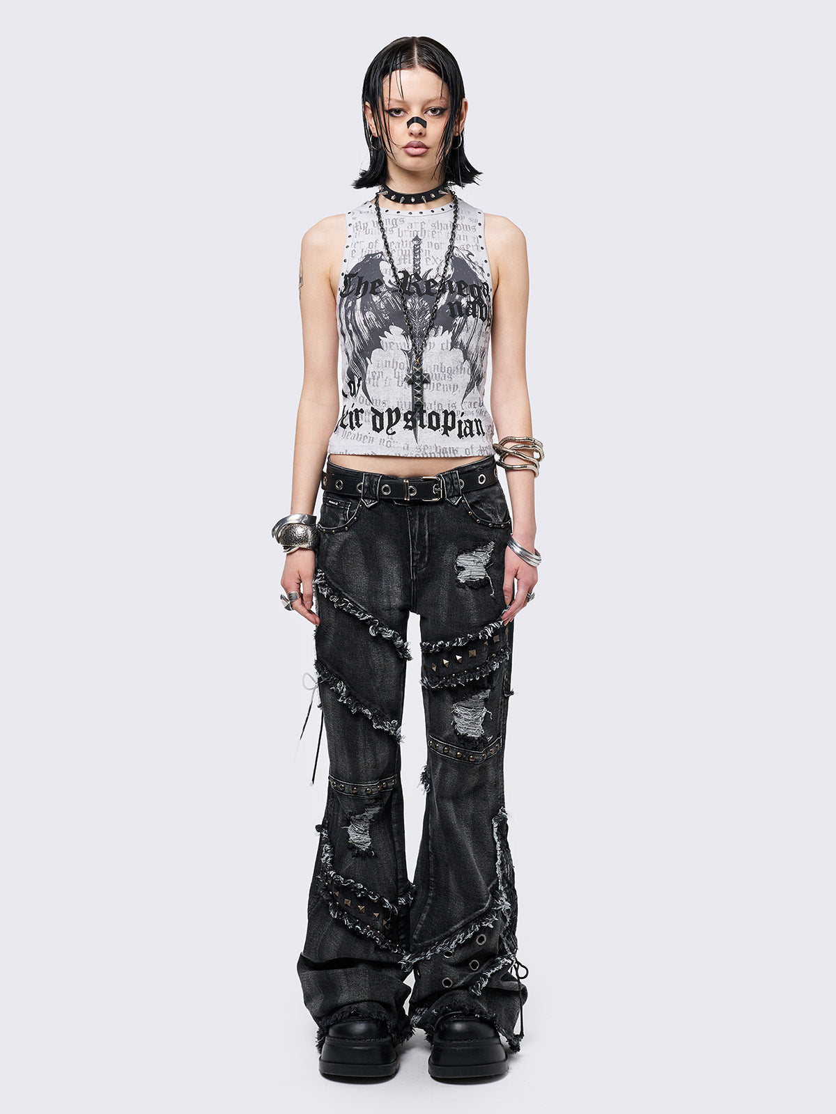Black washed flare jeans with stud, eyelet, lace-up, and distressed details. Grunge-inspired look.