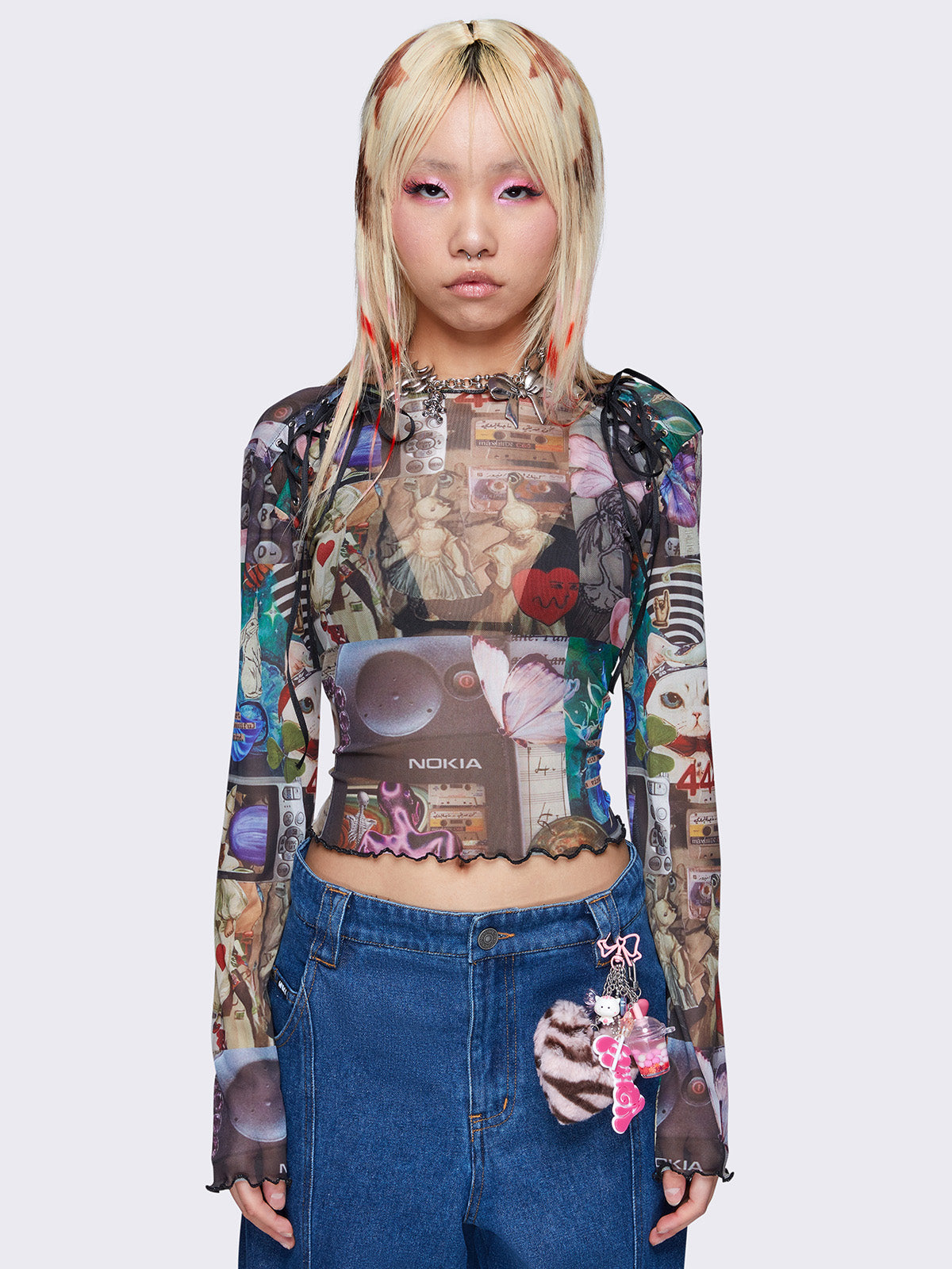 Printed mesh crop top with all over pop art collage graphic print, black lace up details, reverse stitching, and lettuce edge trims.