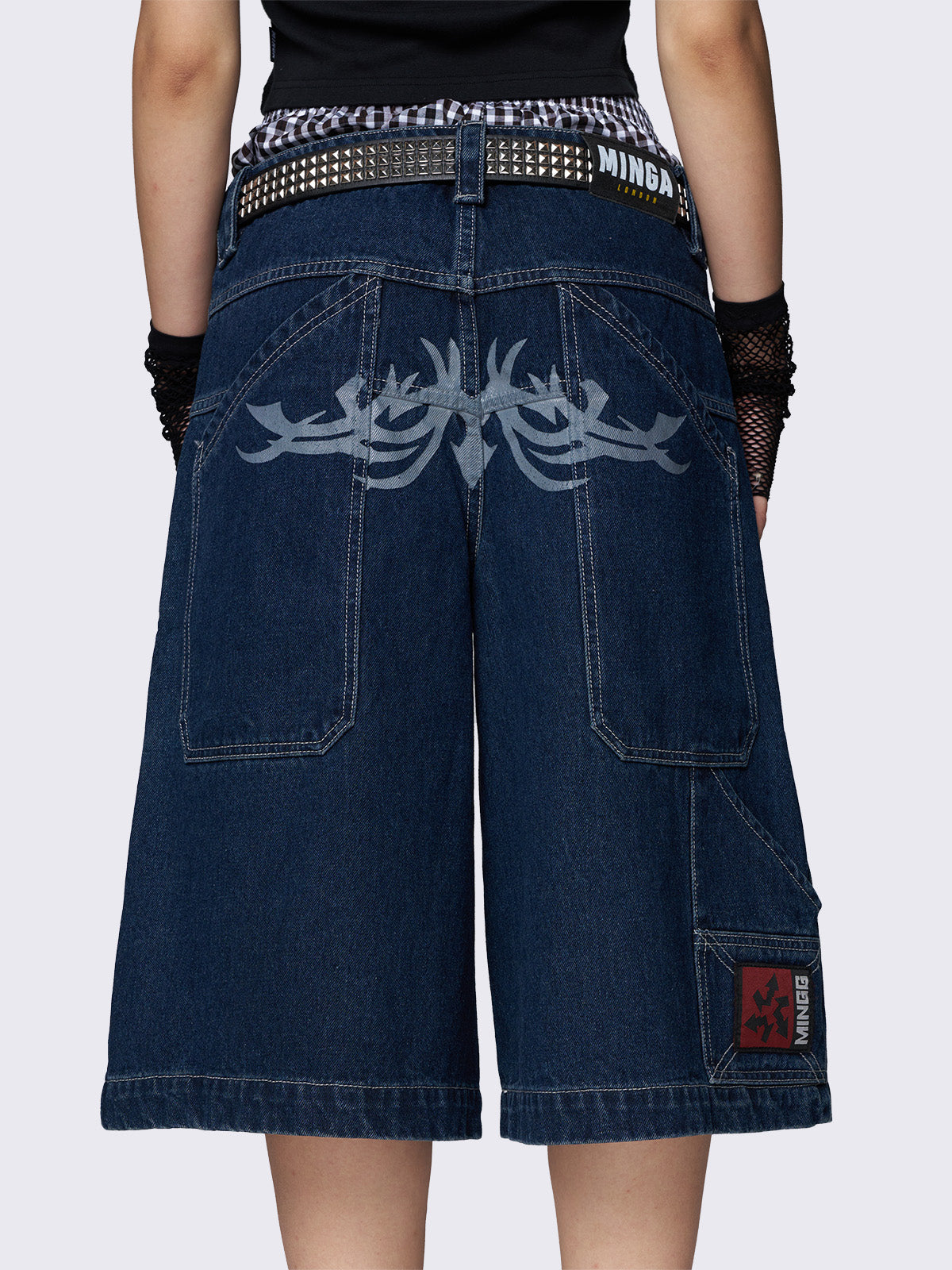 Blue longline denim shorts with carpenter pockets, a tattoo back print, and a relaxed fit. Featuring a regular waist and zip fly with button fastening.
