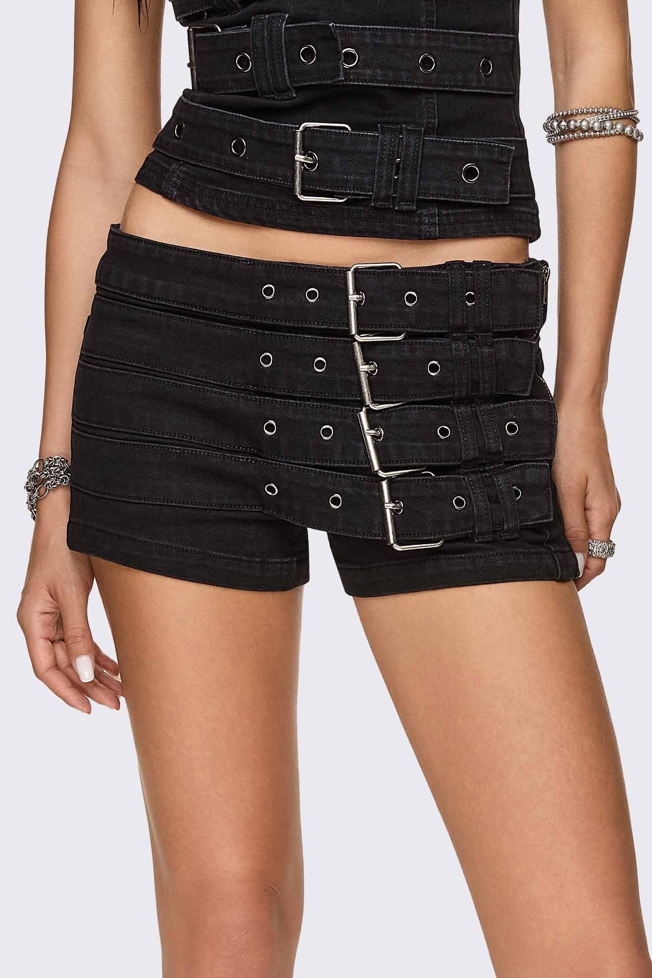 Black washed denim micro shorts with layered buckle straps and low-rise fit in a grunge goth style.