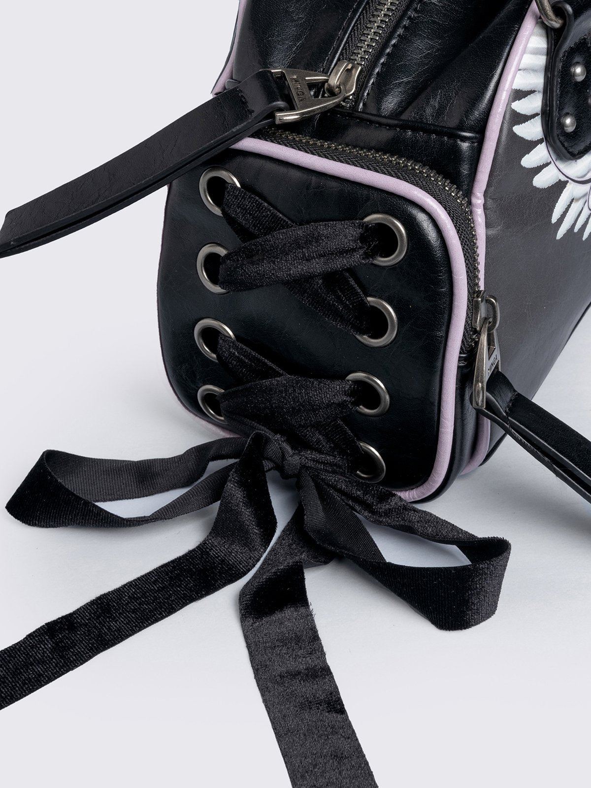Black bowling bag with white wings graphic print, 3D cross metal stud and side exterior pockets with lace up bows.