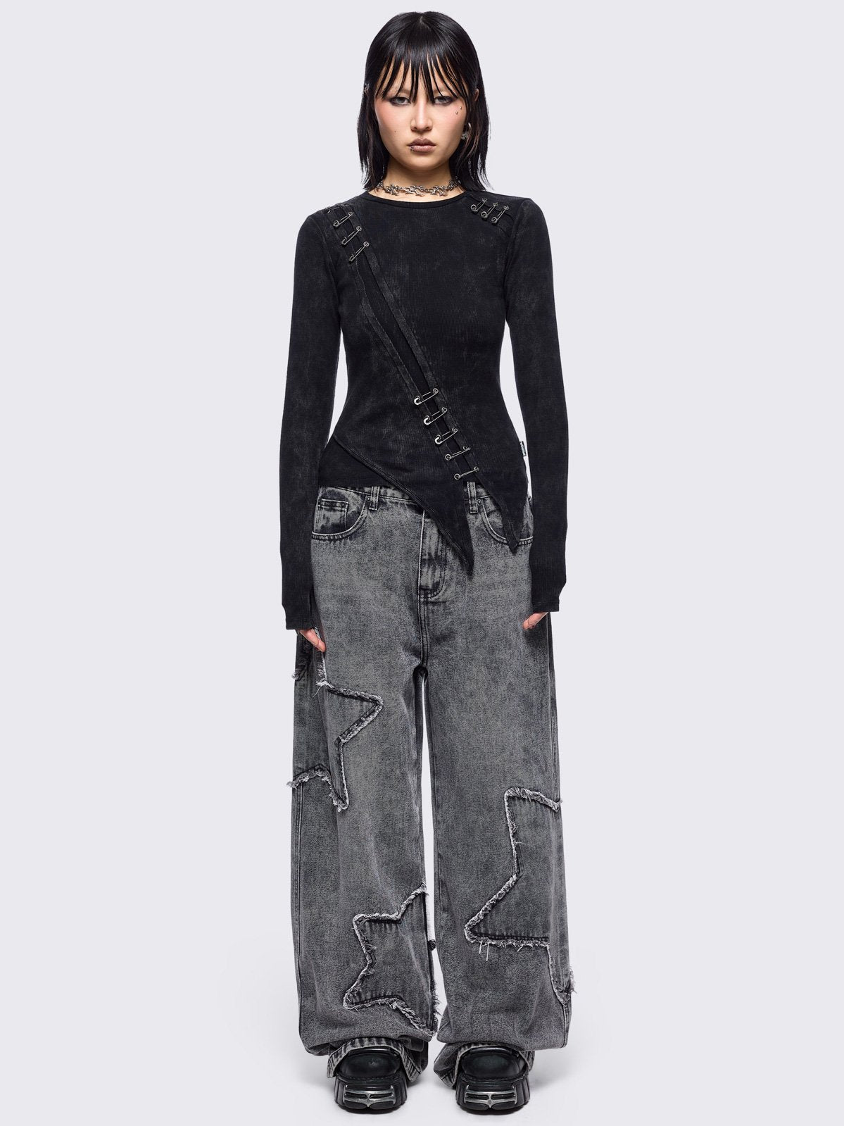 Black washed asymmetric top with cut-out and safety pin details.