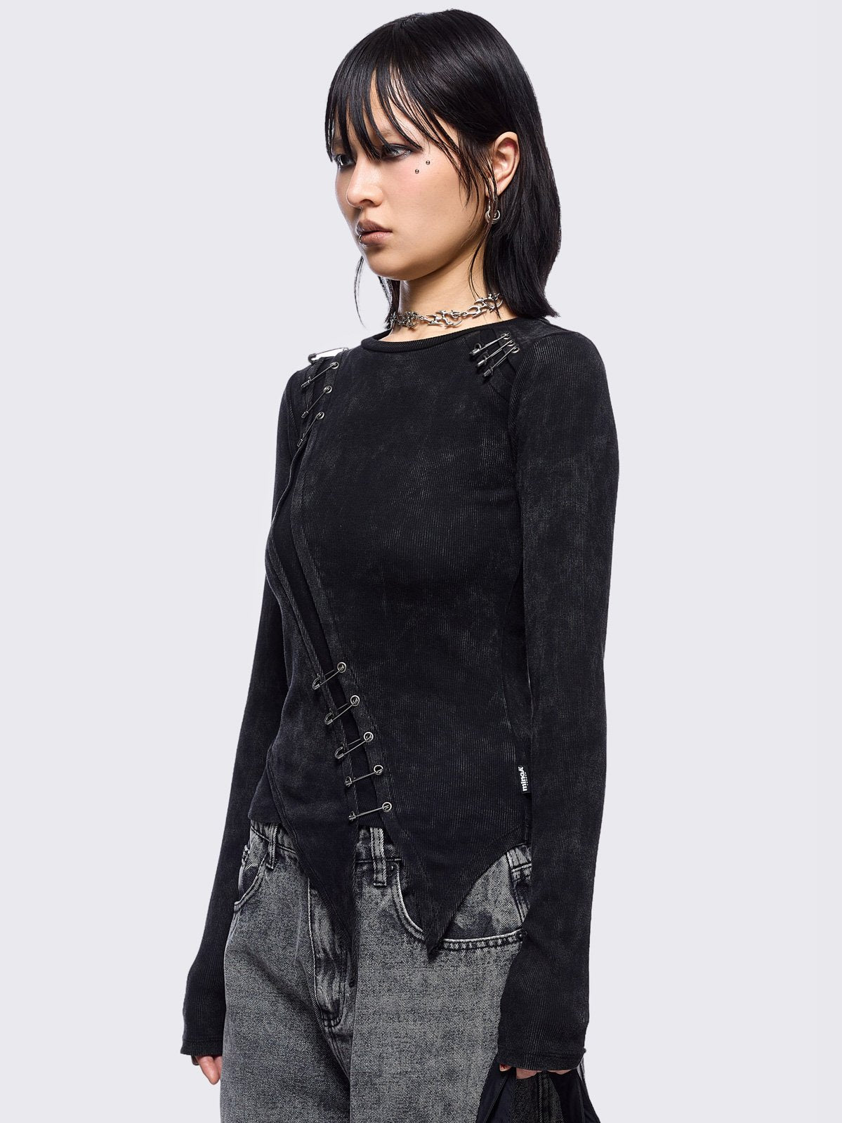 Black washed asymmetric top with cut-out and safety pin details.