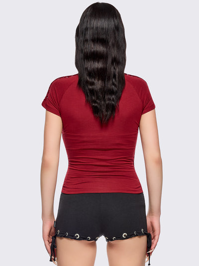 Red slitweave baby tee featuring a black front star patch with piercings.