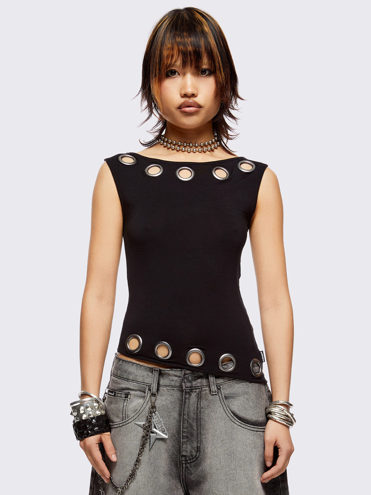 Black asymmetric top with chunky eyelets along neckline and hem and boat neckline.