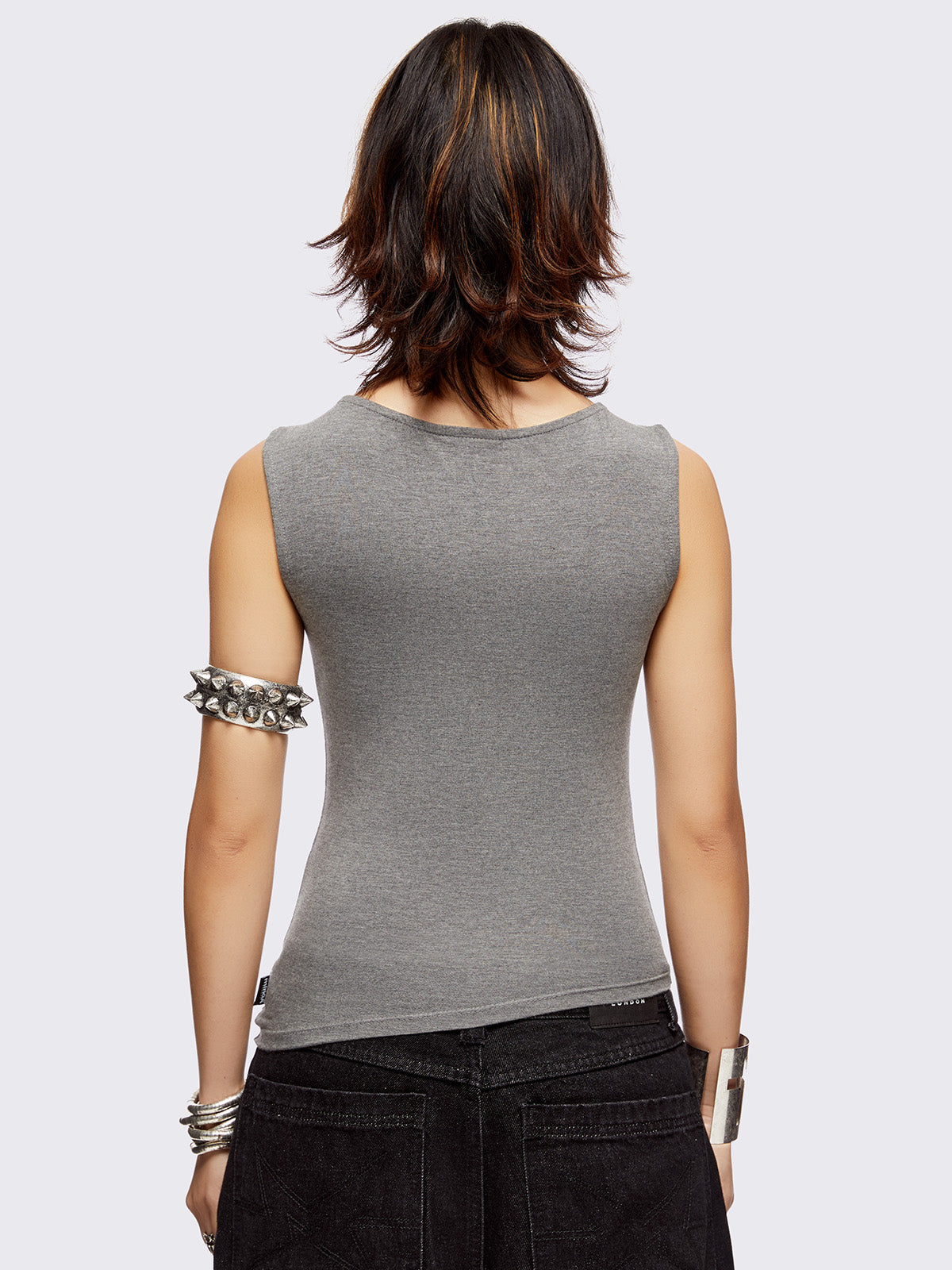 Grey asymmetric top featuring chunky eyelets along neckline and hem and boat neckline.