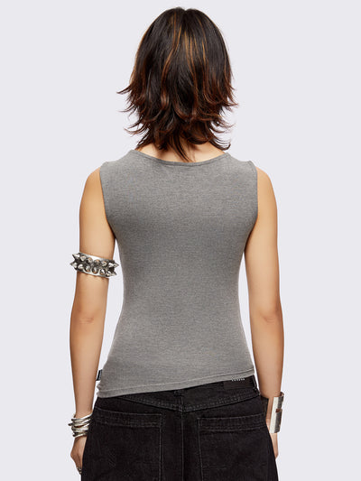 Grey asymmetric top featuring chunky eyelets along neckline and hem and boat neckline.