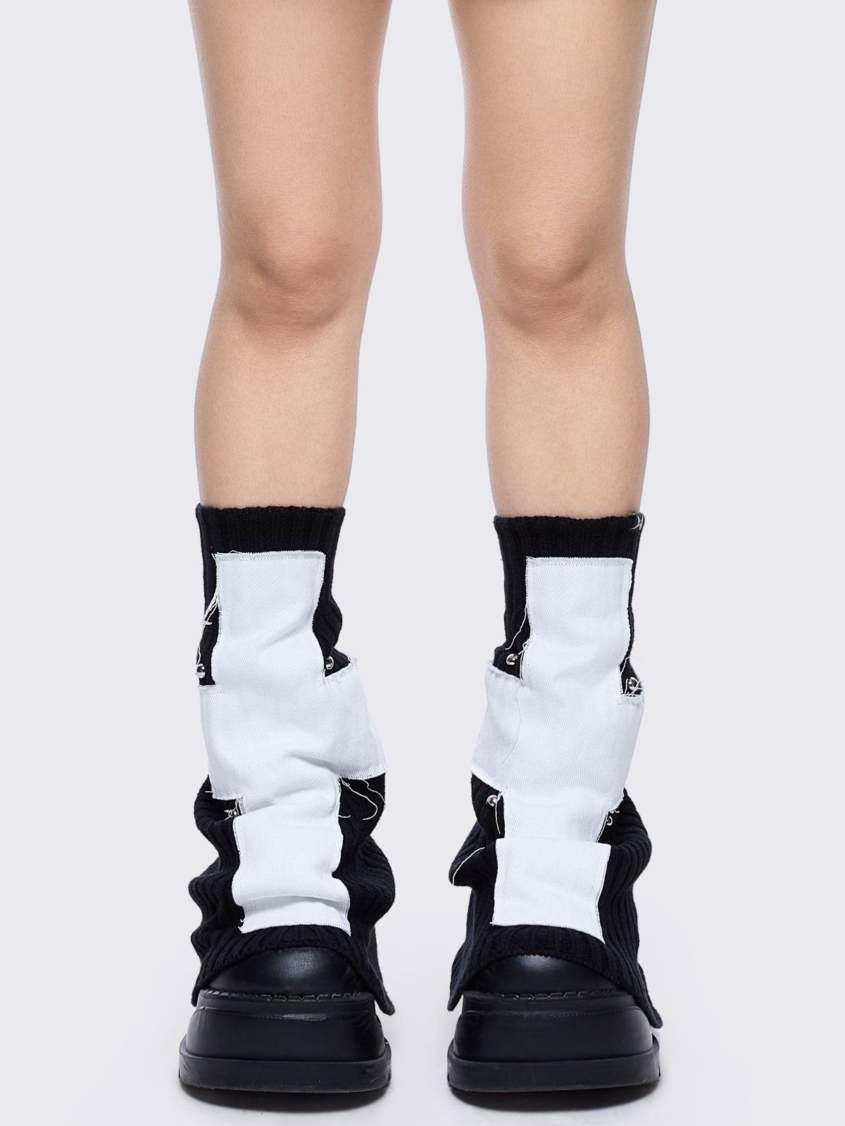 Black knitted flare leg warmers featuring a white chunky cross patch 