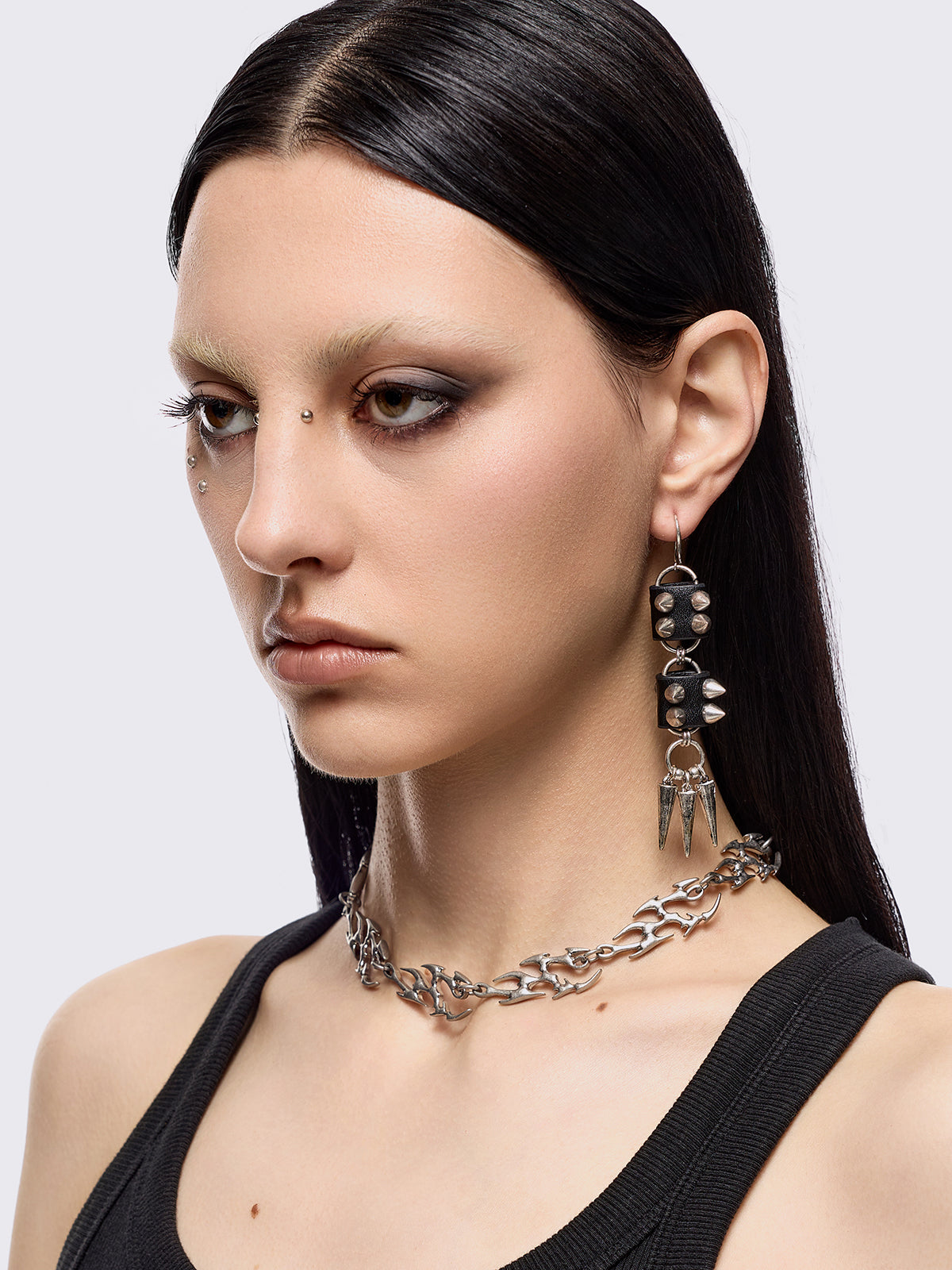 Silver dangle earrings with spiked pendants and black faux leather details