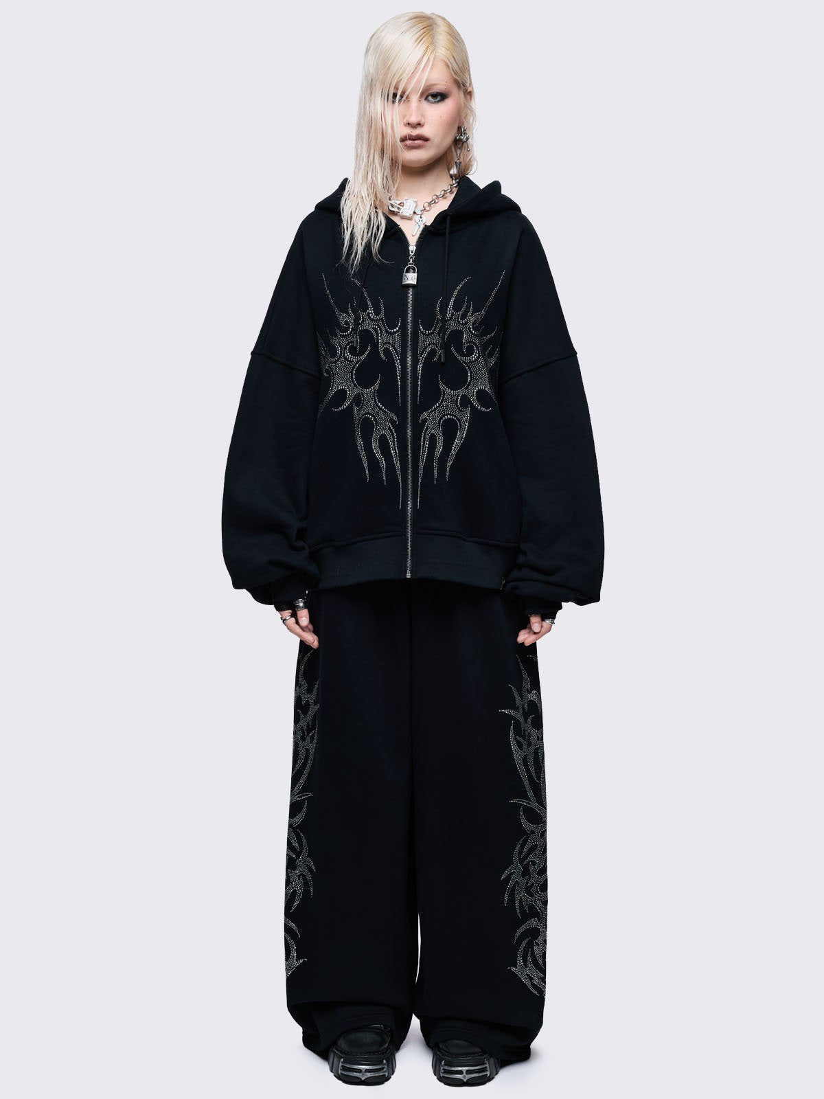 Loose-fit wide-leg sweatpants featuring a large, detailed tribal sigil pattern made of silver rhinestones running down the side seam.