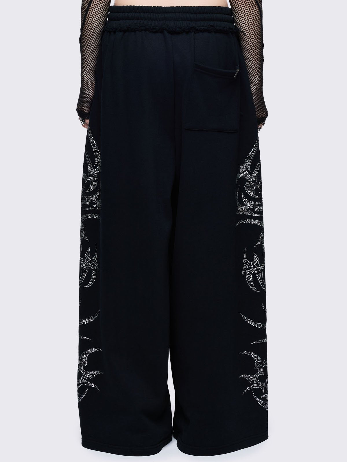 Loose-fit wide-leg sweatpants featuring a large, detailed tribal sigil pattern made of silver rhinestones running down the side seam.