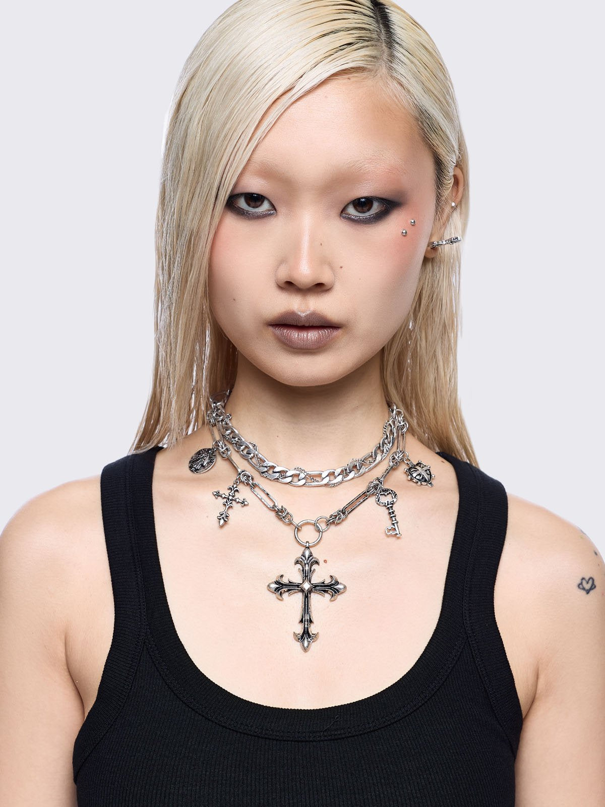 Silver chunky layered necklace featuring cross, key and medallion pendants.