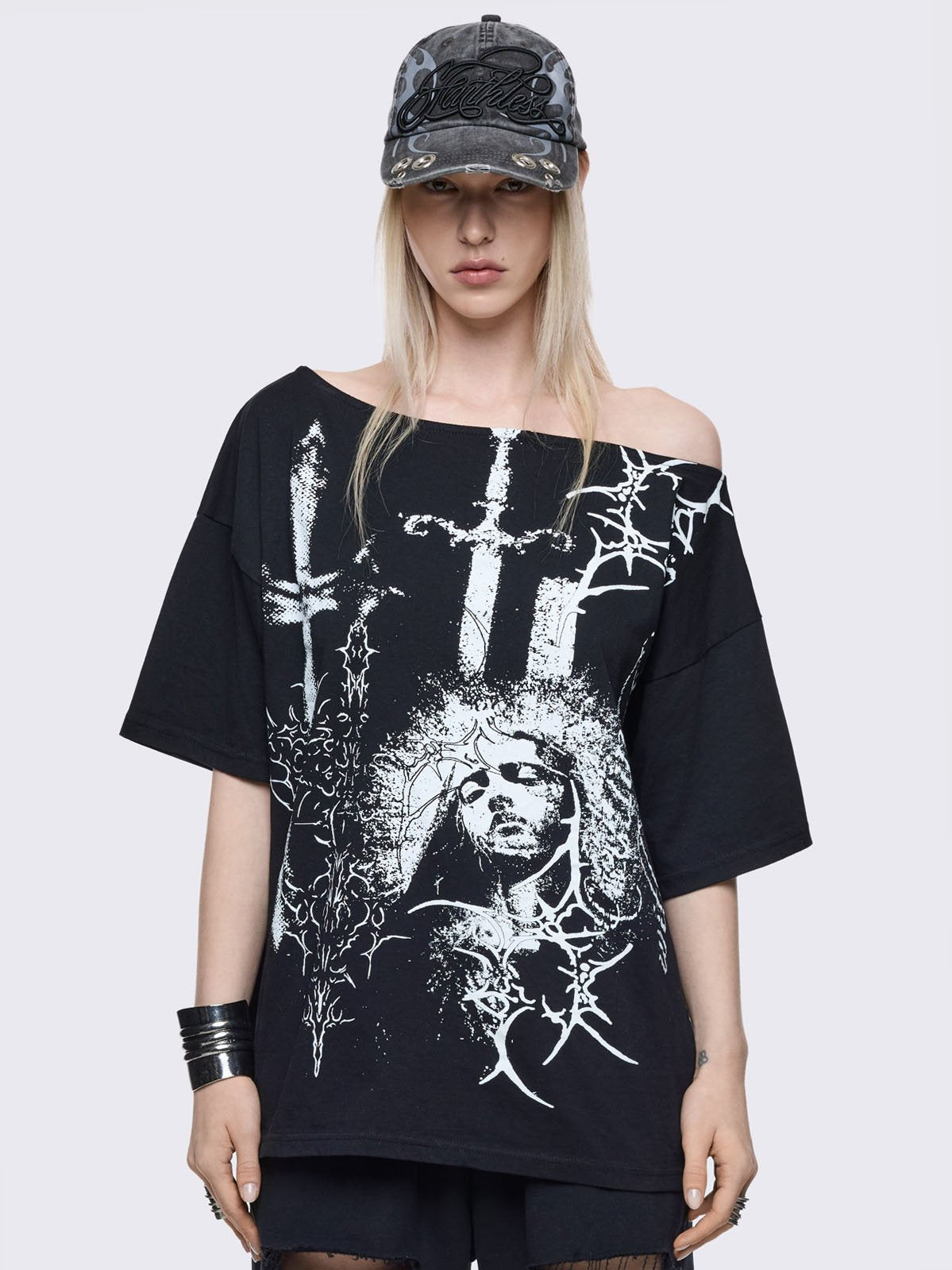 Black off-shoulder t-shirt with saint, daggers and thorns graphic front print.