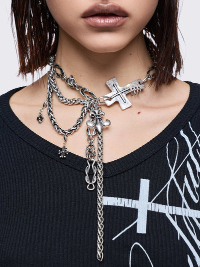 Layered necklace with chunky cross, fleur-de-lis and chain pendants.