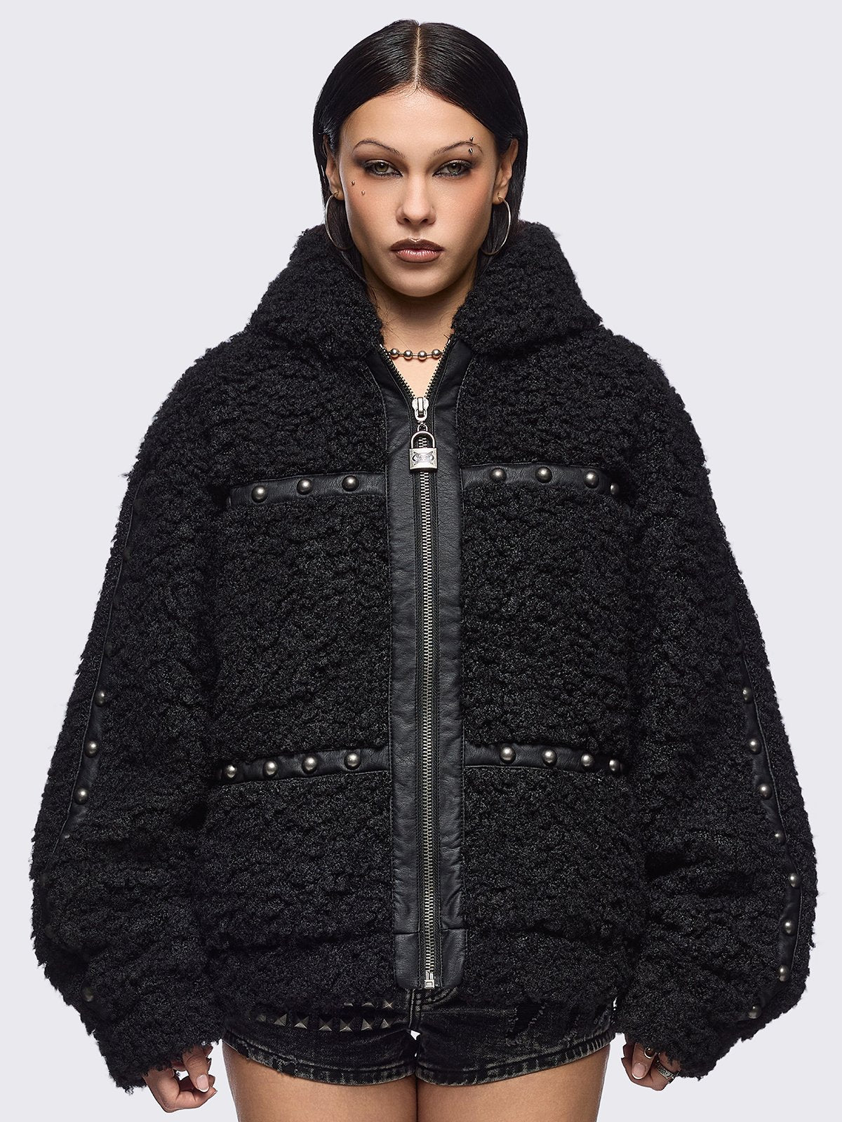 Black faux fur coat featuring a bunny ear hood and faux leather details with silver studs.