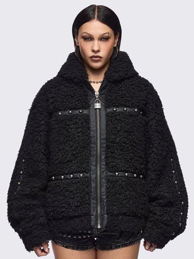 Black faux fur coat featuring a bunny ear hood and faux leather details with silver studs.