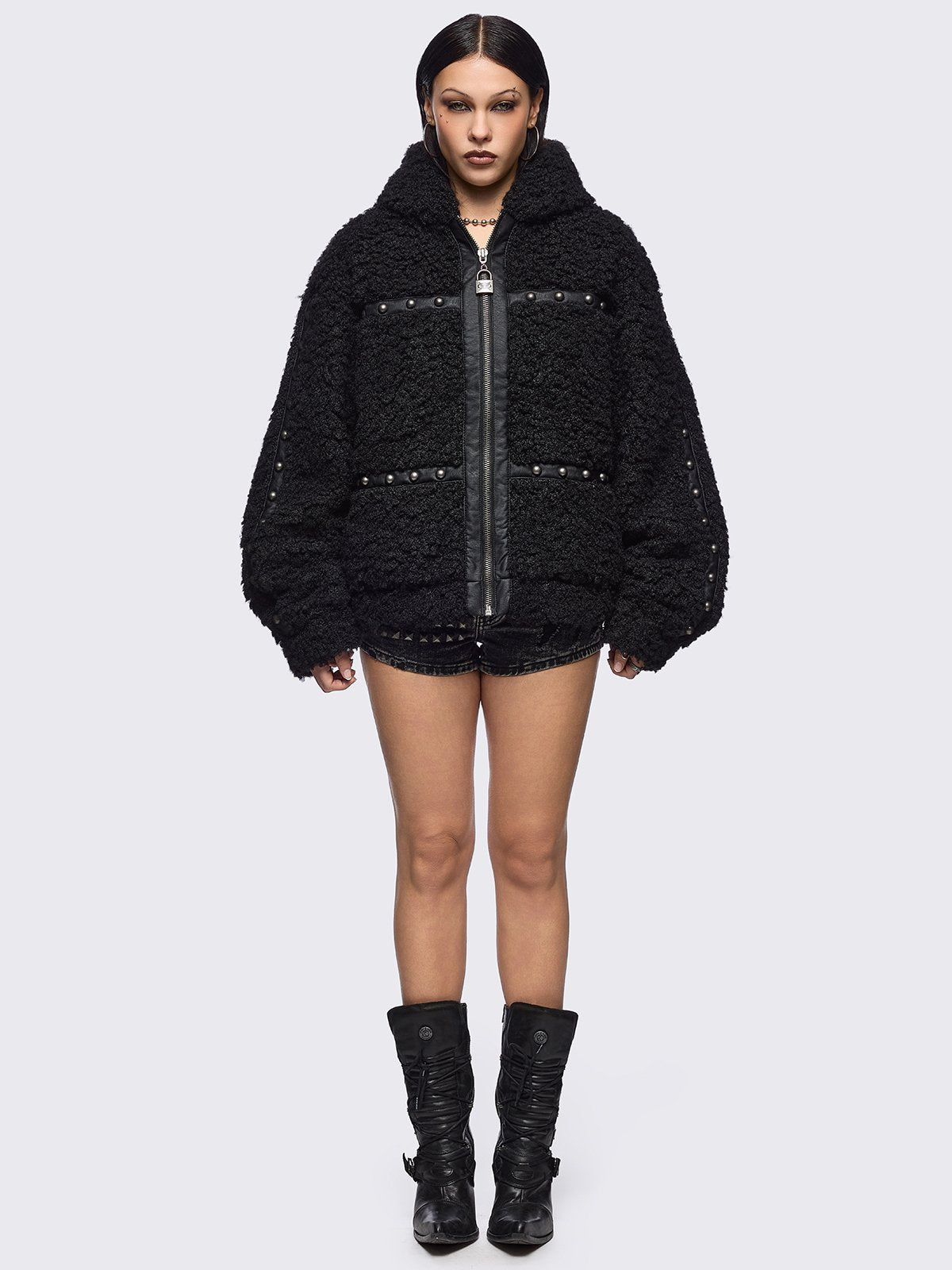 Black faux fur coat featuring a bunny ear hood and faux leather details with silver studs.