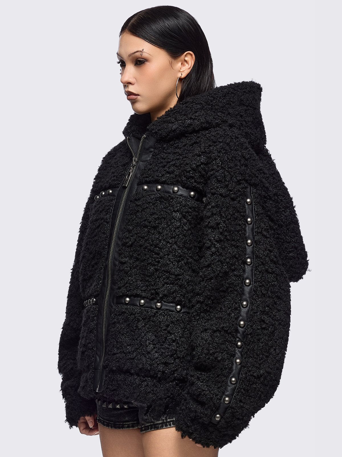 Black faux fur coat featuring a bunny ear hood and faux leather details with silver studs.