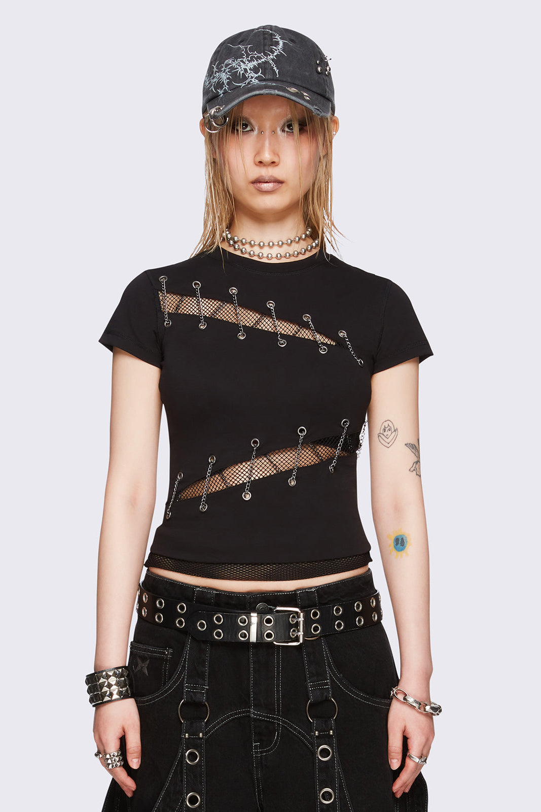 Black baby tee with diagonal fishnet cut-outs, eyelet and chain lace-up details, and short sleeves.