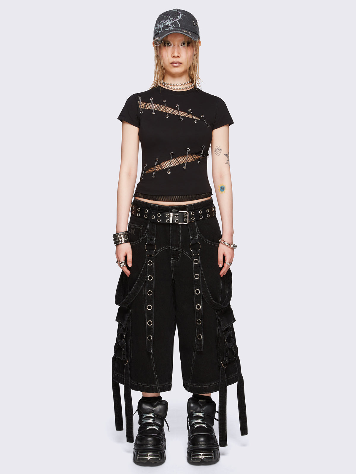 Black baby tee with diagonal fishnet cut-outs, eyelet and chain lace-up details, and short sleeves.