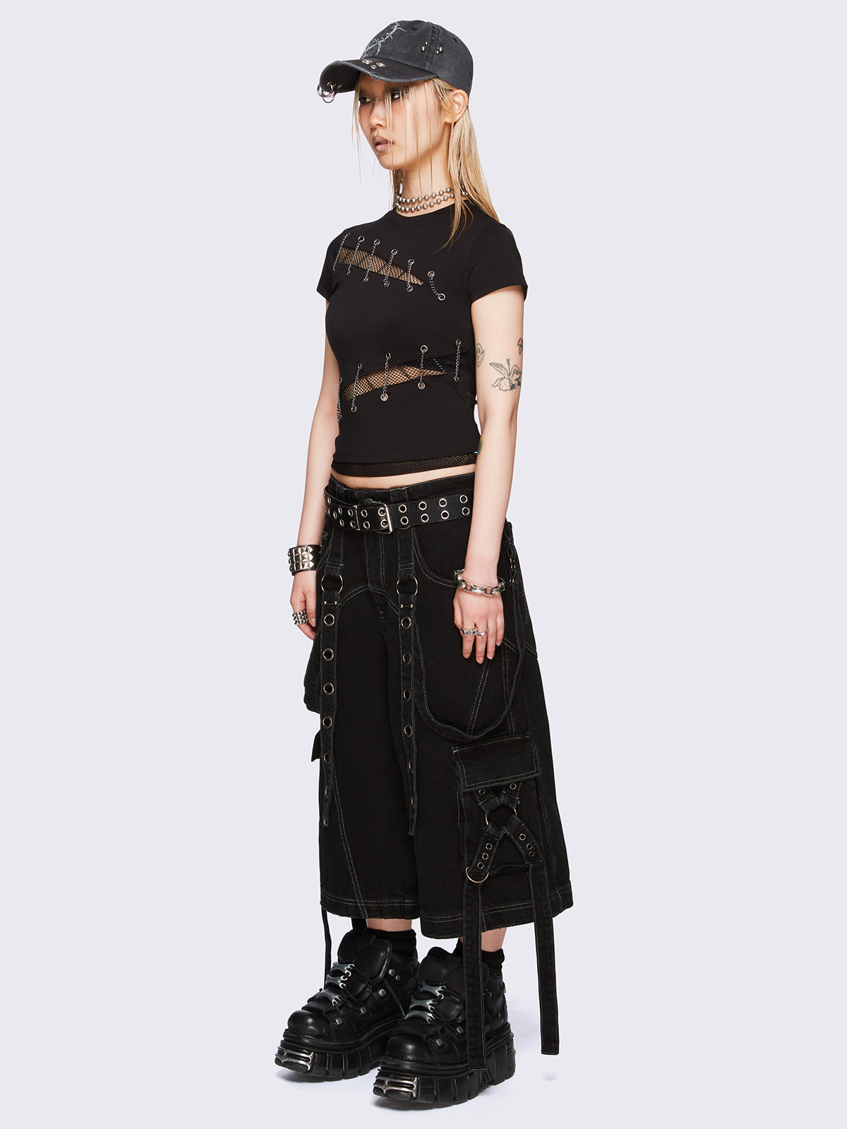 Black baby tee with diagonal fishnet cut-outs, eyelet and chain lace-up details, and short sleeves.