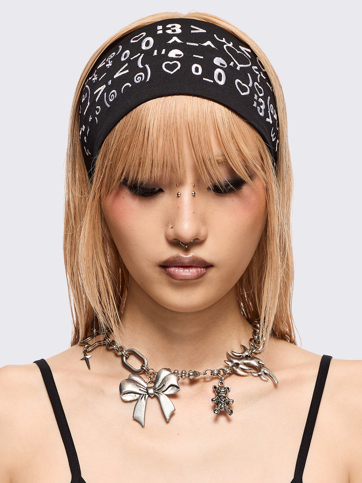 Black wide headband with white kaomoji ASCII-style graphic embroidery.