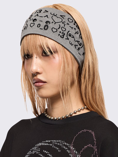 Grey wide headband with black kaomoji ASCII-style graphic embroidery.