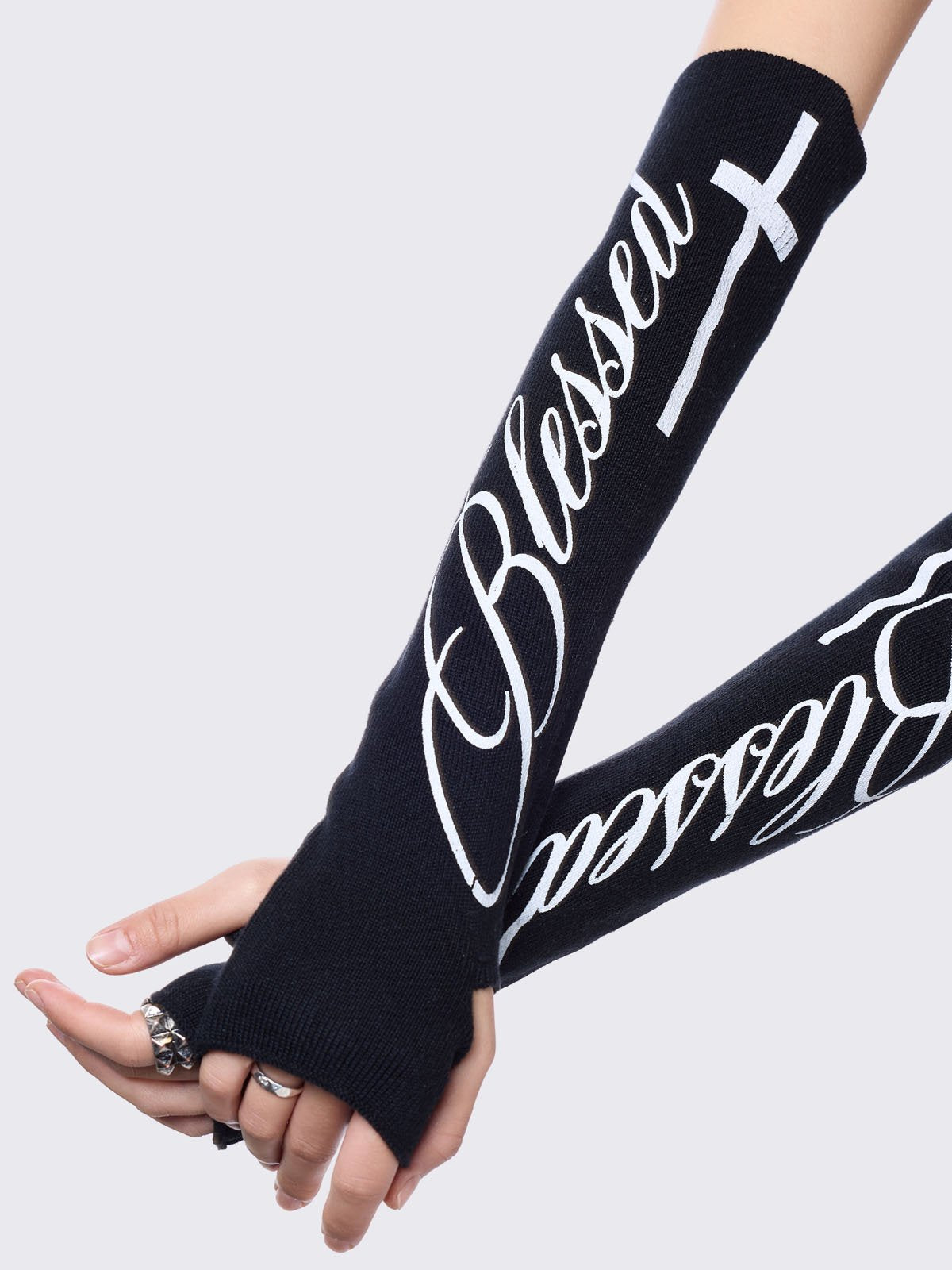 Black knitted arm warmers with white "blessed" cross print.