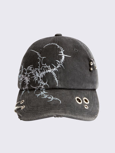 Black washed baseball cap with sigilism graphic print and distressed, eyelet and piercing details.