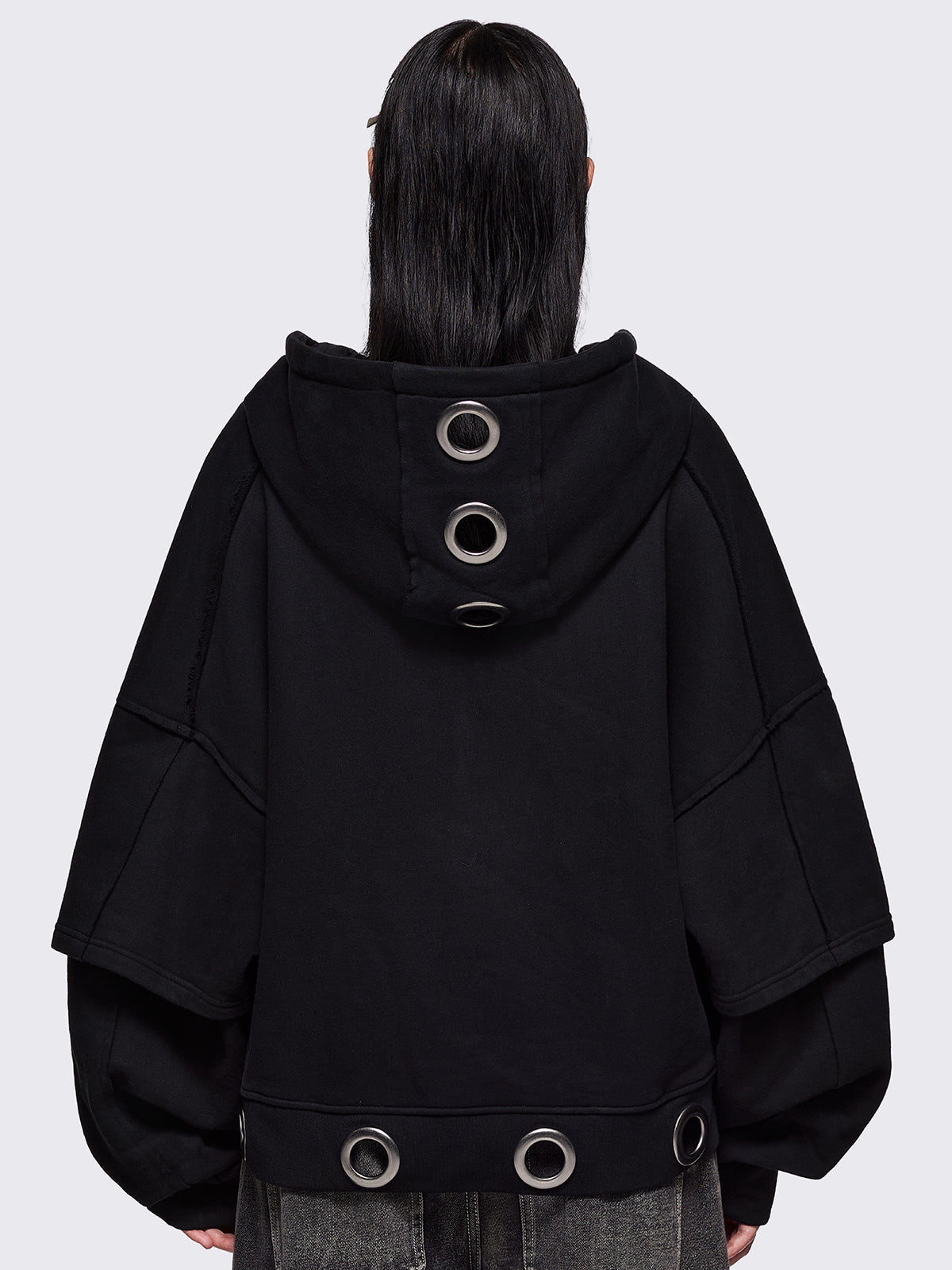 Black layered zip up hoodie, with chunky silver eyelets, raw edge seam details and Minga embroidery.