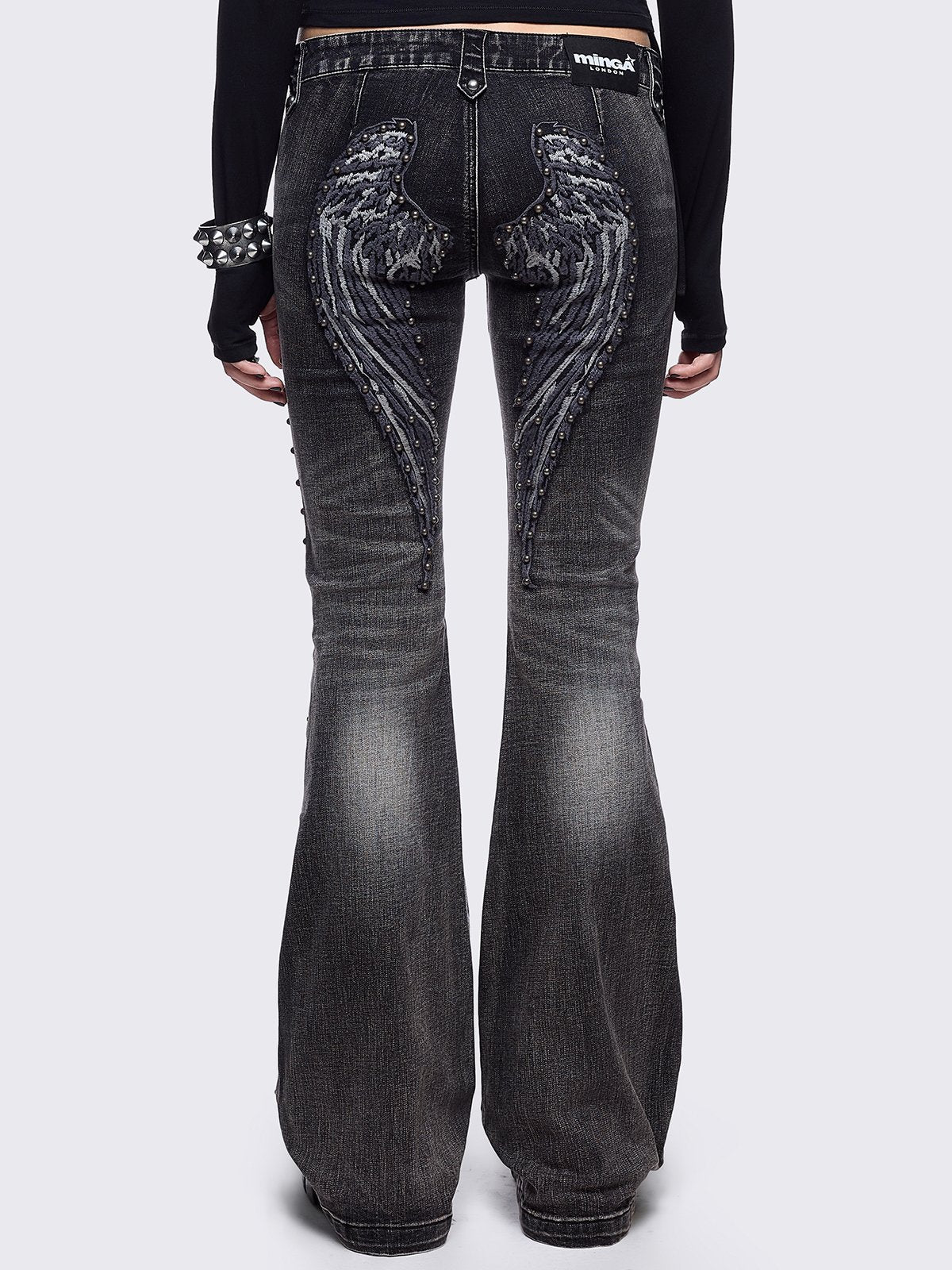 Black washed flared jeans featuring wings back and cross front embroideries and stud trim and details