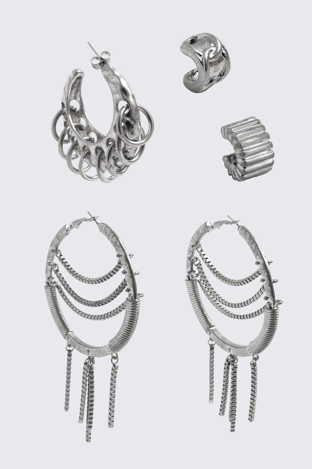 Silver chunky earring set in oxidized metal with hoops, ear cuff and chain details, in a grunge Y2K style.