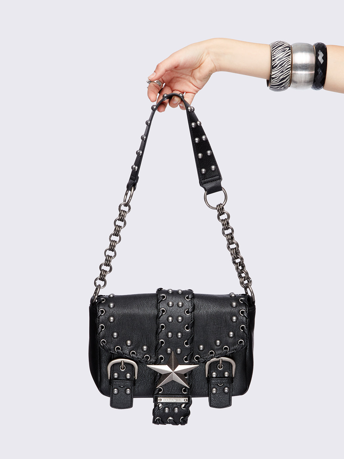 Black grunge-style shoulder bag with silver studs, star detail, chain strap, and buckle accents – edgy festival or streetwear accessory